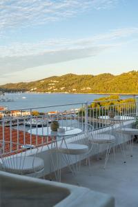 a balcony with tables and chairs and a view of the water at Noemia Skiathos in Skiathos