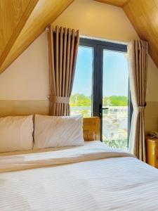 a bedroom with a bed and a large window at Dalat Mist House - Đà Lạt in Da Lat