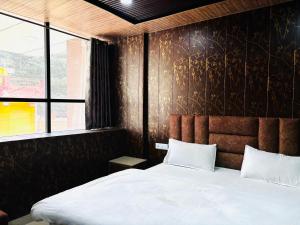 a bedroom with a bed and a large window at JB Hotel and Resort in Lohaghāt