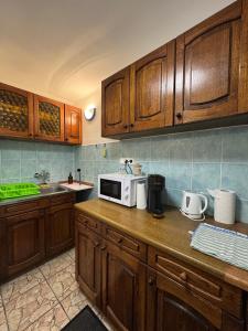 a kitchen with wooden cabinets and a microwave on a counter at Viktória Apartman DunaWeekend in Makád