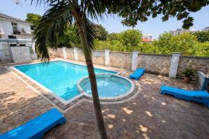 a swimming pool with a palm tree in a yard at Ary Homestay Nyali At Shikara Apartments 5th Avenue Nyali, Mombasa, Kenya in Mombasa