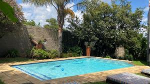 a large swimming pool in a yard with trees at Villa Via Hotel Midrand in Midrand