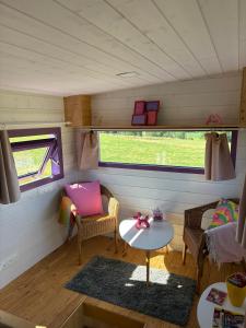 a small room with a table and chairs in a tiny house at La Tiny de Papa un logement Eco-responsable in Saint-Pierre-le-Chastel +24 photos