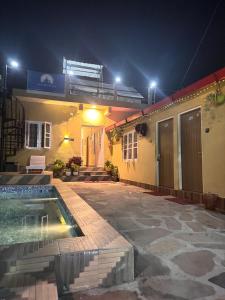 a house with a swimming pool at night at Shivay Hotel & Resort in Dhārchula