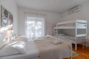 a white bedroom with two beds and a window at Tinka, Zimmer No 5 in Starigrad