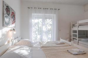a white bedroom with two beds and a window at Tinka, Zimmer No 5 in Starigrad +9 photos