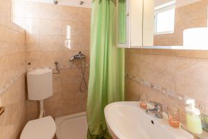 a bathroom with a toilet sink and a green shower curtain at Tinka, Zimmer No 10 in Starigrad