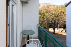 a table on a balcony with a green table at Tinka, Zimmer No 10 in Starigrad
