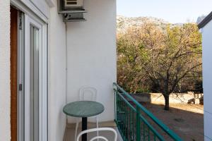 a green stool on a balcony with a table at Tinka, Zimmer No 10 in Starigrad