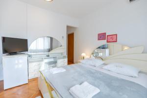 a white bedroom with a large bed and a tv at Tinka, Zimmer No 2 in Starigrad