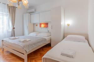 two beds in a room with white walls and wood floors at Tinka, Zimmer No 3 in Starigrad