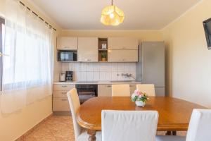 a kitchen with a wooden table and white chairs at Antonija in Bašić