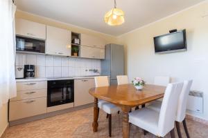 a kitchen and dining room with a wooden table and white chairs at Antonija in Bašić