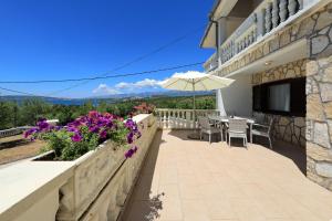 a balcony of a house with a table and an umbrella at Antonija in Bašić