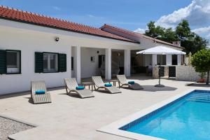 a villa with a swimming pool and chairs and a house at Holiday house Luca with private pool in Vrsi