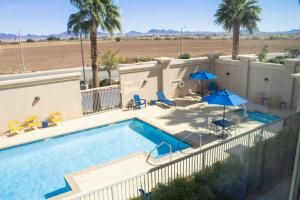 a swimming pool with two umbrellas and chairs at Hampton Inn & Suites Blythe, CA in Blythe