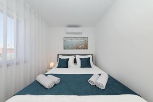 a white bedroom with a bed with blue pillows at Holiday house Luca with private pool in Vrsi +53 photos