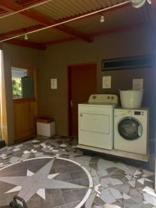 a room with a washing machine and a tile floor at Fare Te Ava Iti in Teahupoo
