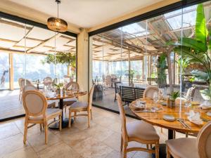 a restaurant with wooden tables and chairs and large windows at Hôtel de la Mer in Hyères
