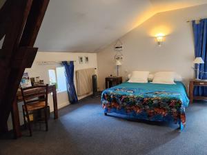 a bedroom with a bed and a desk in it at Hote de l'île chez Wendy et Fred in Jumeaux