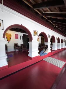 a person sitting on a red floor in a building at Keloth Tharavadu in Panamaram
