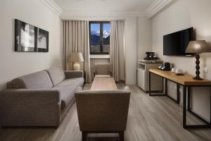 a living room with a couch and a desk and a television at Parador de Vielha Spa & Wellness in Vielha