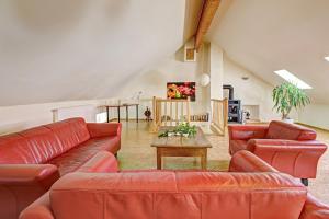 a living room with red leather couches and a table at Nengshof Ferienhaus Königskerze in Wißmannsdorf