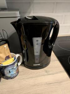 a black tea kettle sitting on a counter next to a cup at White Pebbles Appartment in Ilfracombe