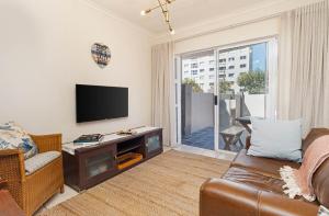 a living room with a couch and a flat screen tv at The Sands Cottage in Cape Town