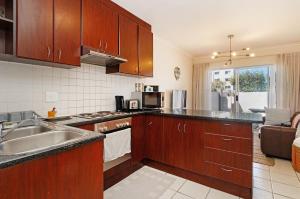 a kitchen with wooden cabinets and a sink at The Sands Cottage in Cape Town
