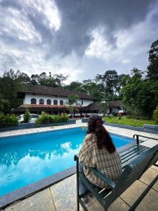 a woman sitting on a bench next to a swimming pool at Keloth Tharavadu in Panamaram +50 photos