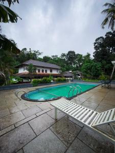 a white bench sitting next to a swimming pool at Keloth Tharavadu in Panamaram