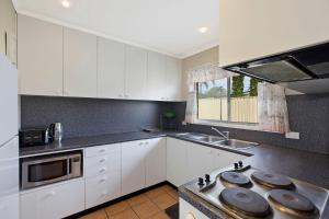 a kitchen with white cabinets and a stove top oven at Fravent house in Toukley +3 photos