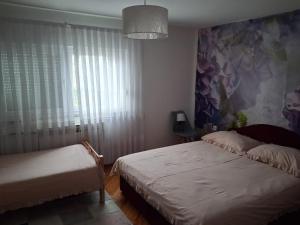 a bedroom with two beds and a painting on the wall at Apartment Upper Town in Gospić