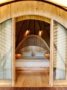 a bed in a wooden house with glass walls at Cocoon Reserve in Kuta Lombok +24 photos