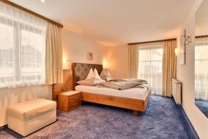 a bedroom with a bed and a large window at Pension Regina in Lech am Arlberg