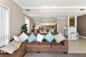 a living room with a brown couch with pillows at The Gallipoli Residence in Long Jetty