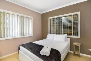 a bedroom with a bed with white towels on it at The Gallipoli Residence in Long Jetty