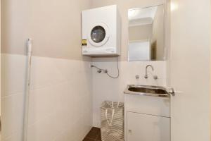 a small bathroom with a sink and a microwave at The Gallipoli Residence in Long Jetty
