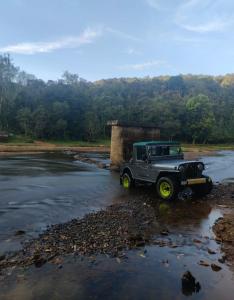 a gray jeep parked in the middle of a river at COORG CLlMATE FARM HOUSE in Madikeri