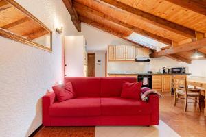 a red couch in a living room with a kitchen at Val di Sole Apartment in Monclassico