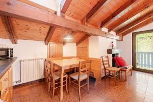 a kitchen and dining room with a wooden table and chairs at Val di Sole Apartment in Monclassico +30 photos