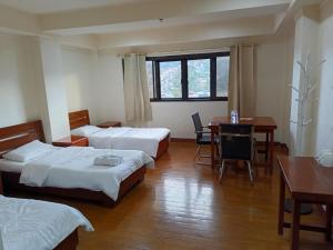 a room with three beds and a table and a desk at Zhongkebole Suites in Baguio +24 photos