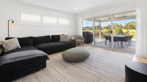 a living room with a black couch and a table at 21 Forever in Pokolbin