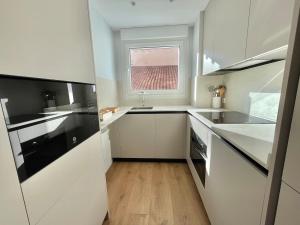 a white kitchen with a sink and a window at Acariciando la Catedral by apartamentoscatedralcamino in Burgos
