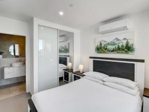 a white bedroom with a large bed and a bathroom at Bay View 2-Bedroom Apartment in Batemans Bay