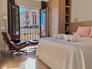 a bedroom with a bed and a chair and a window at Acariciando la Catedral by apartamentoscatedralcamino in Burgos