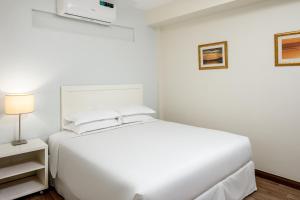 a white bedroom with a large white bed and a lamp at Constellation Apartments in Kampala +16 photos