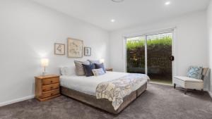 a bedroom with a bed and a chair and a window at Dashaz Dream - The Vintage in Pokolbin