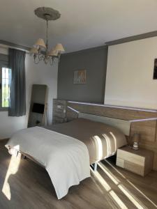 a bedroom with a large bed and a chandelier at La Loma de Alcalá in Arcos de la Frontera +15 photos